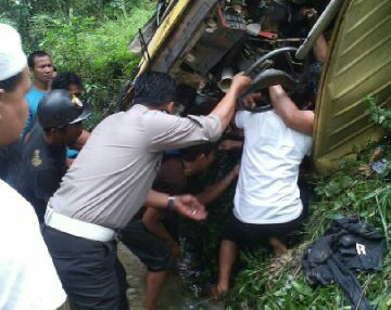 Anggota Satlantas Polres Kuansing berusaha mengeluarkan sopir dan kernet yang mobilnya terjungkal masuk sungai.