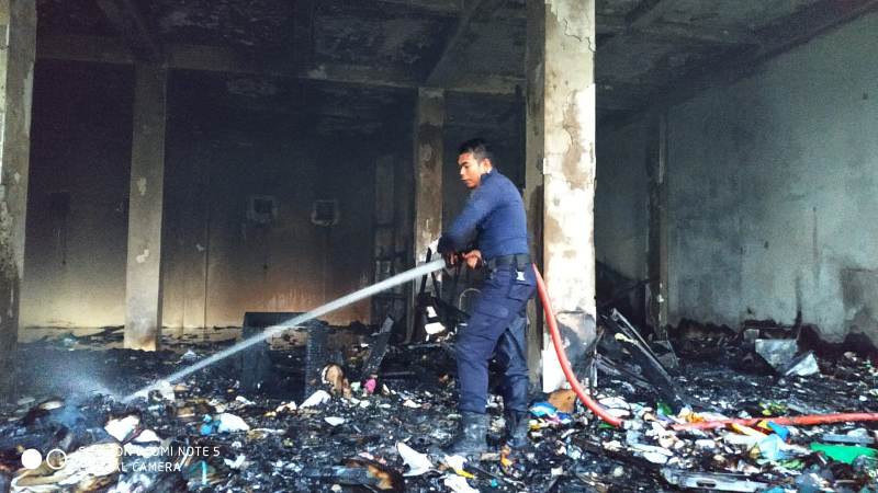 Salah seorang petugas Damkar tengah memadamkan api di gudang arsip milik Pemkab Kuansing yang terbakar.