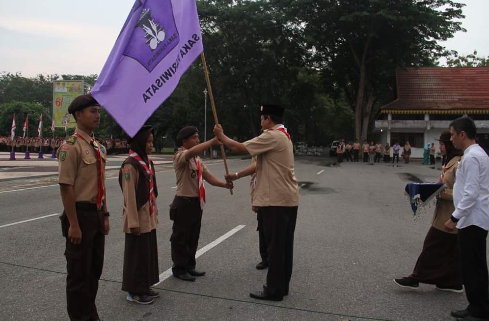 Sekda Inhu saat menyerahkan bendera pramuka kepada anak pramuka pertanda pembukaan perkemahan satuan karya pramuka (SAKA) pariwisata kwartir cabang Indragiri Hulu tahun 2019.