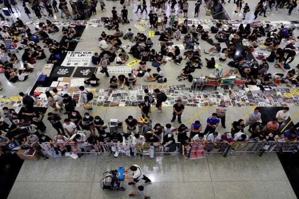 Para pemrotes RUU Anti-Ekstradisi membagikan selebaran kepada para penumpang selama demonstrasi massa di bandara internasional Hong Kong, di Hong Kong, China, 13 Agustus 2019. FOTO: Reuters