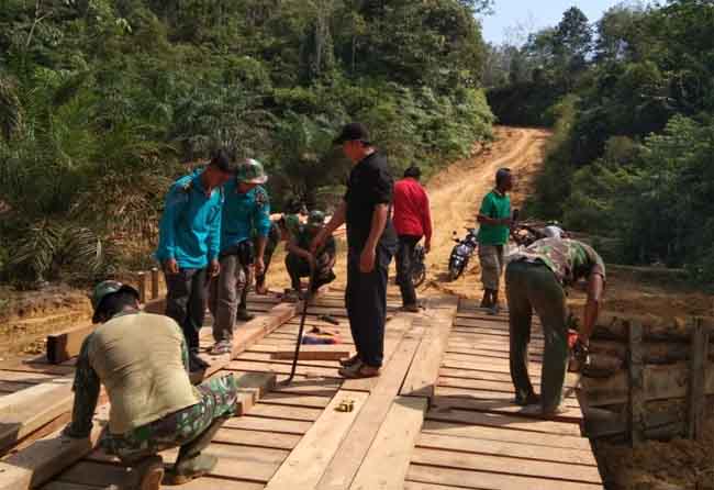 Prajurit TNI bersama warga bekerjasama membangun jembatan penyeberangan di Desa Balung.