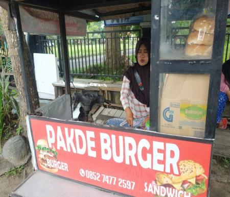 Zulfaidar, pemilik usaha Pakde Burger sedang menyiapkan pesanan pelanggan (foto/riki)