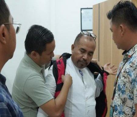 Penyidik Kejari Siak memakaikan rompi tahanan kepada Kalaksa BPBD Siak, Kaharuddin, Jumat (17/5/2024). 