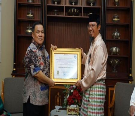 Pj Gubri, SF Hariyanto menerima piagam penghargaan dari Kepala Perwakilan Ombudsman RI di Provinsi Riau, Bambang (foto/int)