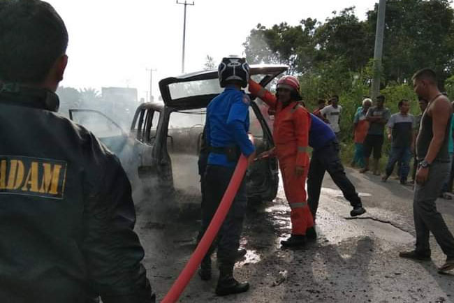    Petugas pemadam kebakaran Kunto Darussalam, memadamkan api yang membakar mobil LGX milik  BM 1702 TC  yang dikendarai Janwardi juga membakar kedua tangannya, usai mengisi minyak di SPBU Kembang Damai Kecamatan Kunto Darussalam.