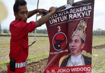 Seorang kader PDIP sedang mencopot poster Jokowi.