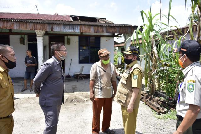 Plh Bupati Bustami berbincang-bincang dengan anggota DPRD Bengkalis Hendri dengan background salah seorang rumah warga yang terdampak bencana alam.