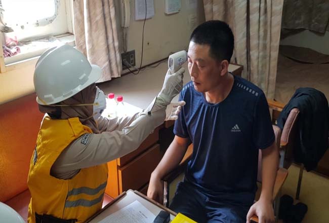 Petugas Kesehatan KKP Dumai memeriksa suhu tubuh ABK asal China menggunakan termometer gun.