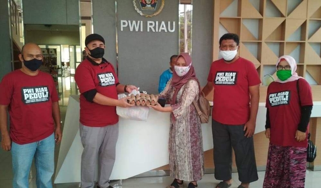 Ketua PWI Riau, H Zulmanayah Sekedang menyerahkan sembako kepada salah seorang wartawati senior, Luzi Diamanda