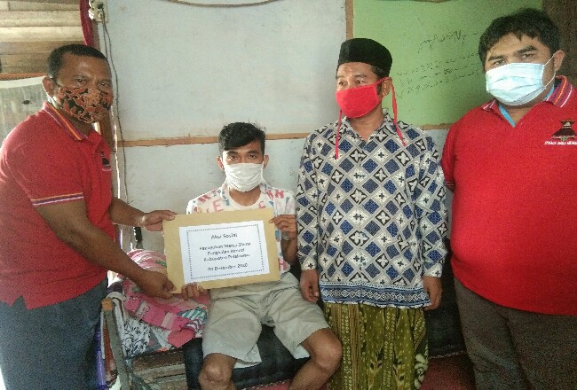 Disaksikan Ketua Paguyuban Merga Silima, Mulya Tarigan, Waka Paguyuban Merga Silima, Piala Subakti, memberikan bantuan sosial pada Faisal. 