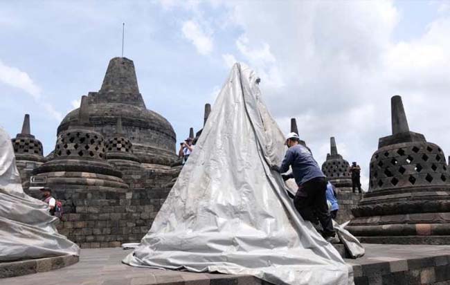 Petugas Balai Konservasi Borobudur menutup stupa candi dengan terpal paulin untuk mengntisipasi erupsi Gunung Merapi. FOTO: ANTARA