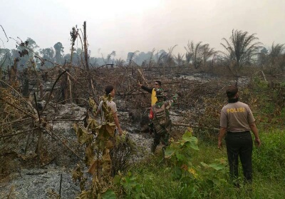 Anggota Polsek Kuantan Mudik bersama Koramil Kuantan Mudik tengah berada di lahan yang terbakar.