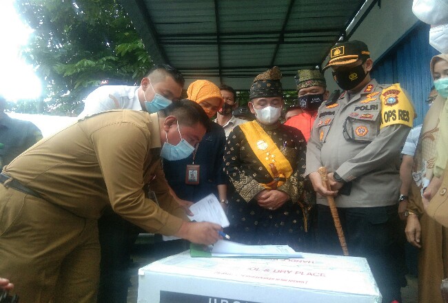 Disaksikan Bupati Pelalawan HM Harris dan Kapolres Pelalawan AKBP Indra Widjatmiko, Kadiskes Pelalawan Asril SKM, MKes menunjukkan tanda terima penyerahan vaksin Sinovac. 