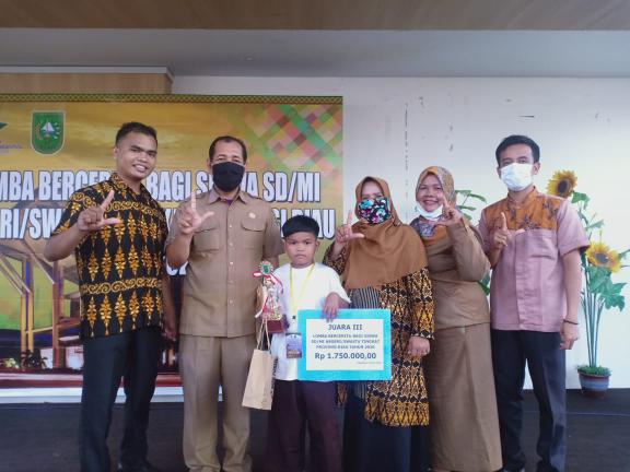 Alfarabi Khawarizmi, pelajar Kelas V SD Muhammadiyah Pasir Pangaraian, menunjukan hadiah yang diterimanya setelah berhasil sabet juara III lomba dongeng tingkat Riau
