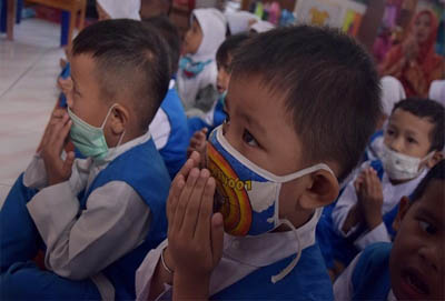 Anak-anak mengenakan masker di dalam ruangan.