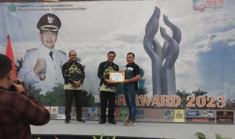 Pj Bupati Pamekasan Masrukin memberikan piagam penghargaan CSR Award kepada Territory Sales Manager XL Axiata Area Madura, Maidi (foto/ist)