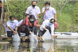 Bupati Kuansing Mursini dan Dekan Faperta UIR Siti Zahrah menebar benih ikan di Danau Tiga Mata Air.