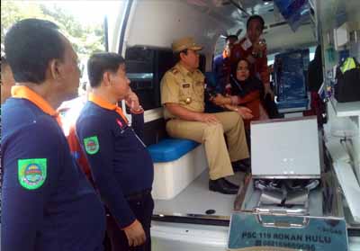   Bupati Sukiman, disaksikan Sekda dan Kadinskes, mencoba memeriksa darah di atas mobil ambulance PSC 119 yang diluncurkan Dinkes, pada peringatan HKN ke 54 di halaman kantor Dinkes Rohul.