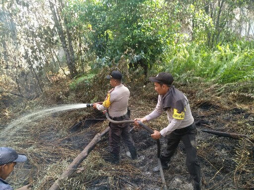 Aparat Polisi Polsek Tebingtinggi sedang memadamkan api di Desa Lukun, Meranti.