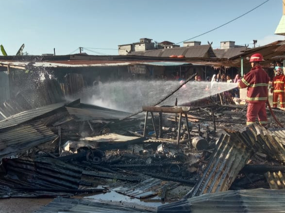 Petugas Damkar BPBD Dumai melakukan pendinginan puing-puing sisa kebakaran kedai nasi di Pasar Pulau Payung Dumai