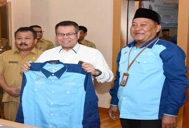 Kepala BPS Bengkalis Sukarwanto menyerahkan Baju BPS kepada Plt Bupati Bengkalis H Muhammad.