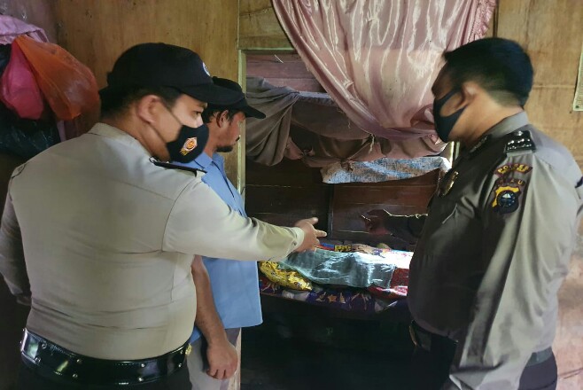 Petugas kepolisian Polsek GAS saat menunjukan jasad korban pasangan suami istei yang meninggal di dalam kamar rumahnya, Rabu (18/11/2020). Foto: Riaupos
