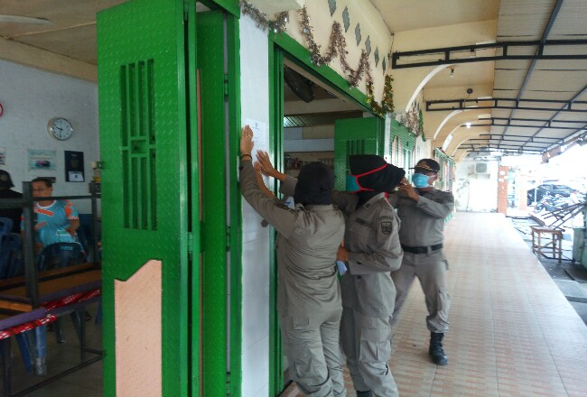 Para petugas gabungan menempelkan selembaran surat edaran ditempat usaha yang ada di kota Bagansiapiapi, Rabu (8/4/2020).