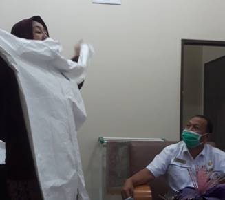 Kadiskopperindah dan UKM, Drs Fakhrizal, melihat salah pelaku UKM di Pelalawan yang tengah memperlihatkan baju APD yang akan dibuatnya.