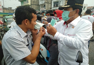 Bupati Sukiman saat memasangkan masker pada pengguna jalan.