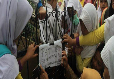 Guru memasang tanda libur sekolah di Pekanbaru. FOTO: Tribun.