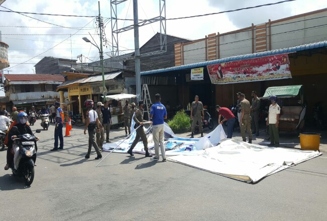 Terlihat anggota Satpol-PP Kepulauan Meranti sedang mencopot baliho dari Billboard yang akan dibongkar di persimpangan Jalan Ahmad Yani- Teuku Umar Selatpanjang.