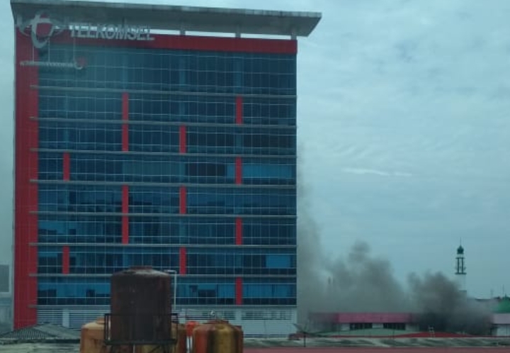 Tampak gedung di lingkungan plasa Telkomsel mengeluarkan asap hitam tanda kebakaran.