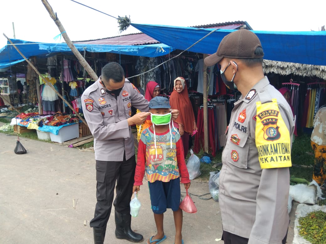 Personel Polsek Bangko membagikan masker di Pasar Pekan Suak Air Hitam. 