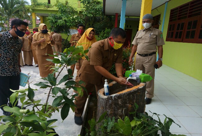 Kadisdik Rohil, HM Nur Hidayat SH mencoba menggunakan tempat cuci tangan milik SDN 008 Bagan Punak disela-sela meninjau kesiapan sekolah itu.