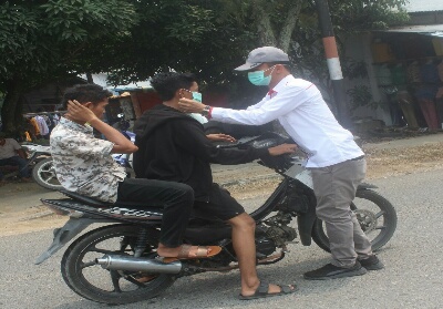 Ketua Pemuda Batak Kuansing Hardianto Manik memasangkan masker pada pengguna jalan.