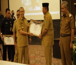 Gubernur Riau Syamsuar menyerahkan piagam penghargaan kepada Bupati Siak Alfedri dalam upaya menurunkan stunting.(foto: diana/halloriau.com)
