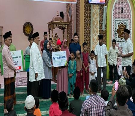 Pj Gubri menyerahkan bantuan kepada ahli waris warga setempat di Masjid Jami Haqqul Yakin, Kampar.(foto: sri/halloriau.com)