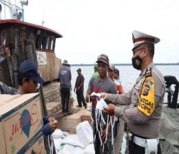 Petugas kepolisian tampak membagikan masker kepada buruh di pelabuhan