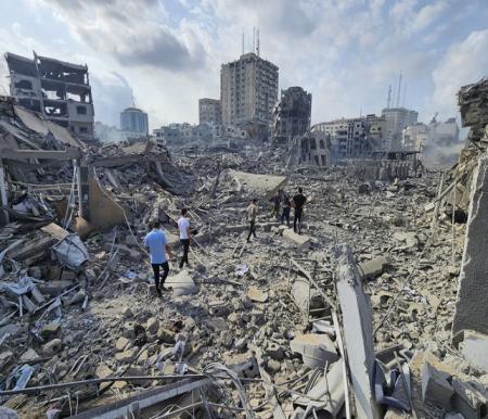 ilustrasi: Warga Palestina berjalan melewati puing-puing bangunan yang hancur akibat serangan udara Israel di Kota Gaza pada Rabu, (11/10/2023) WIB. | AP Photo/Hassan Eslaiah