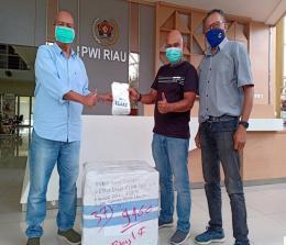 Dinas ESDM Provinsi Riau diwakili salah seorang wartawan, Budy menyerahkan bantuan masker untuk PWI Riau yang diterima Sekretaris PWI Riau, Amril Jambak, Rabu (13/1/2021). Foto IST