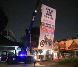 Satpol PP Kota Pekanbaru memotong tiang reklame di halaman Kantor Meteorologi Pekanbaru. 