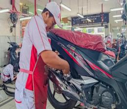 Mekanik sedang melakukan perawatan sepeda motor Honda konsumen di AHASS.(foto: istimewa)