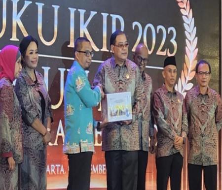 Komisioner KI Provinsi Riau Bidang Advokasi, Sosialisasi dan Edukasi, yang juga anggota Pokjada IKIP Riau, Asril Darma menerima Buku hasil IKIP 2023.(foto: istimewa)