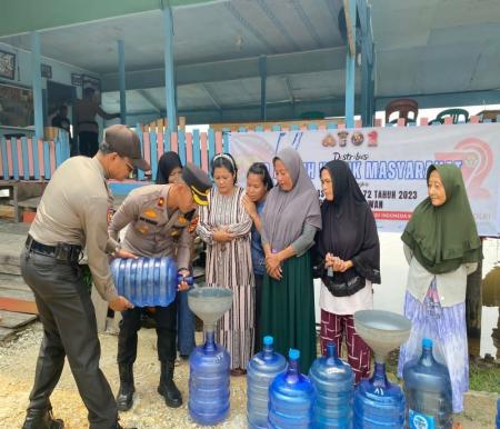 Wakapolres Pelalawan Kompol Dwi Yatmoko bagikan ratusan galon air ke warga (foto/andi)