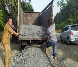 Kades Aliantan M Rois Zakaria, ikut membantu supir truk menurunkan pasir batu untuk menimbun jalan lintas provinsi Riau di Aliantan yang berlubang.