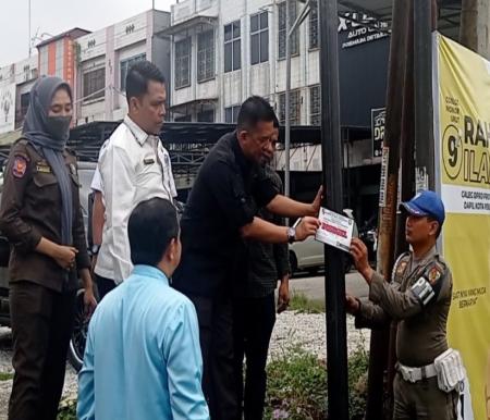 Kasatpol PP Zulfahmi menyegel tiang ilegal milik provider di Kelurahan Labuh Baru Timur (foto/int)