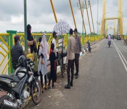 Petugas Polsek Bangko memberikan imbauan terkait penerapan prokes Covid-19 kepada pengunjung Jembatan Pedamaran. 
