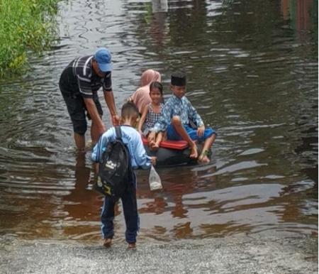 Akibat banjir di Meranti Pandak, Rumbai, siswa naik ban untuk berangkat ke sekolah (foto/riki)