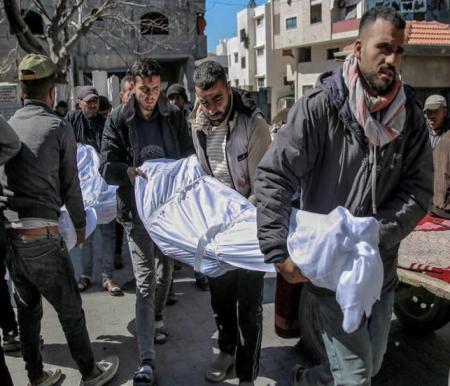 Warga membawa jenazah korban tewas dalam insiden dini hari ketika warga bergegas menuju truk bantuan di Kota Gaza pada 29 Februari 2024. Foto: AFP