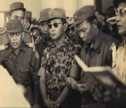 Jenderal Abdul Haris Nasution dan Mayor Jenderal Soeharto berdoa di depan peti jenazah almarhum Jenderal Sutojo Siswomihardjo dan enam rekannya yang gugur dalam Peristiwa 1 Oktober 1965. 